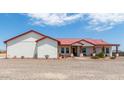 Single story home with red metal roof, covered porch, and gravel driveway at 5604 S 225Th Ave, Buckeye, AZ 85326