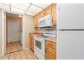 Kitchen with wood cabinets, white appliances, and adjacent laundry room at 13606 N 109Th Ave, Sun City, AZ 85351