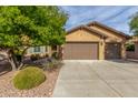 Tan house with brown two-car garage and mature landscaping at 7818 W Montebello Way, Florence, AZ 85132