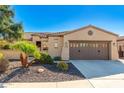 Tan stucco house with a brown garage door and desert landscaping at 27789 N 129Th Ln, Peoria, AZ 85383