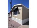 Tan single-wide mobile home with black awnings and American flag at 2600 E Allred Ave # R-95, Mesa, AZ 85204