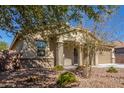 Tan house with a front porch, two-car garage, and drought-tolerant landscaping at 43958 W Stonecreek Rd, Maricopa, AZ 85139