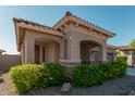 Tan house with a covered entryway, two-car garage, and lush landscaping at 20403 W Calle Encorvada --, Buckeye, AZ 85396