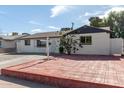 White brick ranch house with a spacious front yard and red brick driveway at 8151 W Clarendon Ave, Phoenix, AZ 85033