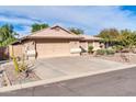 Tan house with a two-car garage and drought-tolerant landscaping at 16128 W Monte Cristo Ave, Surprise, AZ 85374