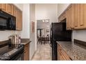 Galley kitchen with granite countertops, wood cabinets, and appliances at 1116 E Belmont Ave, Phoenix, AZ 85020