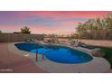 Kidney shaped pool with large rocks and a metal handrail at 10919 S Dreamy Dr, Goodyear, AZ 85338