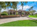 A luxurious two-story home with a stone facade, palm trees, and a large driveway at 19915 E Sonoqui Blvd, Queen Creek, AZ 85142