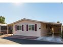 Side view of a tan manufactured home with maroon shutters and carport at 9302 E Broadway Rd # 9, Mesa, AZ 85208