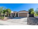 Tan house exterior with a two-car garage and landscaping at 7585 W Tumblewood Dr, Peoria, AZ 85382