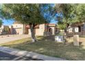 Tan two-car garage with arched entryway and landscaping at 10128 E Minnesota Ave, Sun Lakes, AZ 85248