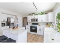 Modern kitchen with white cabinets, large island, and stainless steel appliances at 12243 W Dahlia Dr, El Mirage, AZ 85335