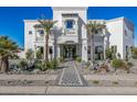 Stunning two-story home with a white stucco exterior, palm trees, and a paved driveway at 1480 E Raven Ct, Gilbert, AZ 85297