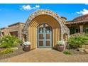 Arched stone entryway with decorative iron gates and landscaping at 9533 E Rising Sun Dr, Scottsdale, AZ 85262