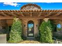 Inviting exterior entrance with stonework, arched metal door, and lush landscaping at 9533 E Rising Sun Dr, Scottsdale, AZ 85262