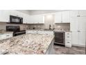 Modern kitchen with granite countertops, white cabinets, and black appliances at 101 W Shannon St, Chandler, AZ 85225