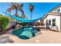 Inviting kidney-shaped pool with a teal shade sail and rock waterfall feature at 10847 E Forge Cir, Mesa, AZ 85208