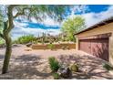 View of a two-car garage with a brown door and brick driveway at 27440 N Alma School Pkwy # 33-1, Scottsdale, AZ 85262