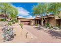 Desert landscape with a Spanish-style home, featuring a large garage and brick driveway at 27440 N Alma School Pkwy # 33-1, Scottsdale, AZ 85262