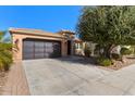 Front view of a tan house with a dark-colored garage door and driveway at 856 E Harmony Way, San Tan Valley, AZ 85140