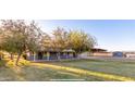 Gray house with a large yard, trees, and outbuildings at 22914 W Sunland Ave, Buckeye, AZ 85326