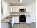 Modern kitchen featuring white cabinets, granite countertops, and stainless steel appliances at 8572 W Raven Dr, Arizona City, AZ 85123