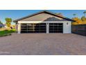 Modern two-car garage with glass paneled doors and a paver driveway at 8701 E Highland Ave, Scottsdale, AZ 85251