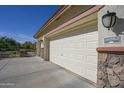 White two-car garage with stone accents and exterior lighting at 26702 N 97Th Ln, Peoria, AZ 85383