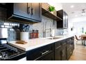 Modern kitchen featuring dark cabinetry, white countertops, and gray tile backsplash at 2143 W Wilshire Dr, Phoenix, AZ 85009