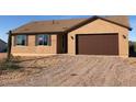 Tan colored house with a brown garage door and a gravel driveway at 4607 N 334Th Ave, Tonopah, AZ 85354