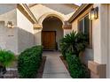 Front entry with arched doorway and lush landscaping at 11957 N 140Th Ln, Surprise, AZ 85379