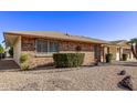 Brick ranch home with well-manicured shrubs and a gravel yard at 19607 N Signal Butte Cir, Sun City, AZ 85373