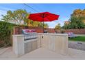 Modern outdoor kitchen with stainless steel appliances and bar seating at 8450 E Montecito Ave, Scottsdale, AZ 85251