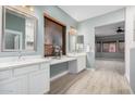 Spacious bathroom with dual vanities, a large mirror, and light-colored wood flooring at 7591 N 87Th Ave, Glendale, AZ 85305