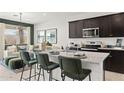 Modern kitchen with dark cabinetry, granite island, and stainless steel appliances at 12157 E Aster Ln, Florence, AZ 85132