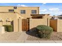 Front view of a stucco townhome with a wooden gate and landscaped walkway at 14011 N 54Th Ave, Glendale, AZ 85306