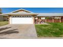 House exterior featuring a white garage door, well-manicured lawn, and a brick walkway at 10728 W Cheryl Dr, Sun City, AZ 85351