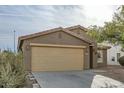 Tan house with a two-car garage, and drought-tolerant landscaping at 25763 W Satellite Ln, Buckeye, AZ 85326