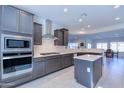 Bright kitchen with gray cabinets, stainless steel appliances, and an island at 6364 W Springfield Way, Florence, AZ 85132