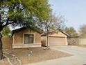 Tan house with a two-car garage and mature tree in front at 8626 W Gross Ave, Tolleson, AZ 85353