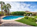 Relaxing kidney-shaped pool with artificial turf and patio at 24816 S Pleasant Ct, Sun Lakes, AZ 85248