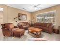 Living room with brown leather furniture, wooden coffee table, and tile floor at 17770 W Calistoga Dr, Surprise, AZ 85387