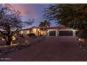 Evening view of a single-story home with a landscaped front yard and a long driveway at 8618 E Santa Catalina Dr, Scottsdale, AZ 85255