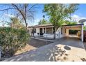 Front view of a renovated white house with a carport and chain link fence at 6107 W Orangewood Ave, Glendale, AZ 85301