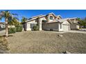 Two-story house with a beige exterior, two-car garage, and desert landscaping at 5618 W Blackhawk Dr, Glendale, AZ 85308