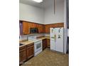 Kitchen with wooden cabinets, tiled floor, and white appliances at 5738 N 68Th Ave, Glendale, AZ 85303