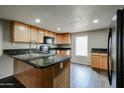 Compact kitchen with wood cabinetry, dark granite countertops, and black appliances at 625 W Mckellips Rd # 161, Mesa, AZ 85201