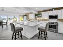 Modern kitchen with white cabinets, large island, and stainless steel appliances at 13626 N Tan Tara Pt, Sun City, AZ 85351