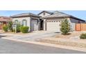 House exterior showcasing a two-car garage and neatly landscaped front yard at 16406 W Charlotte Dr, Surprise, AZ 85387