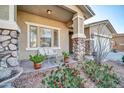 Front porch with stone columns, seating, and potted plants at 17655 W Acapulco Ln, Surprise, AZ 85388